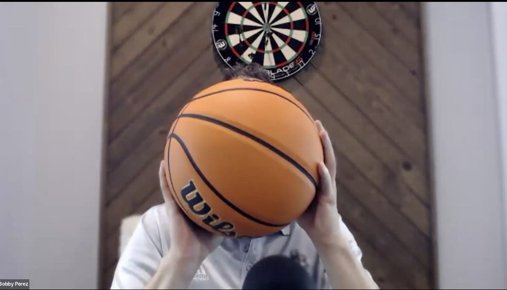 The coach on a live call holding a ball up to the camera to demonstrate a set point