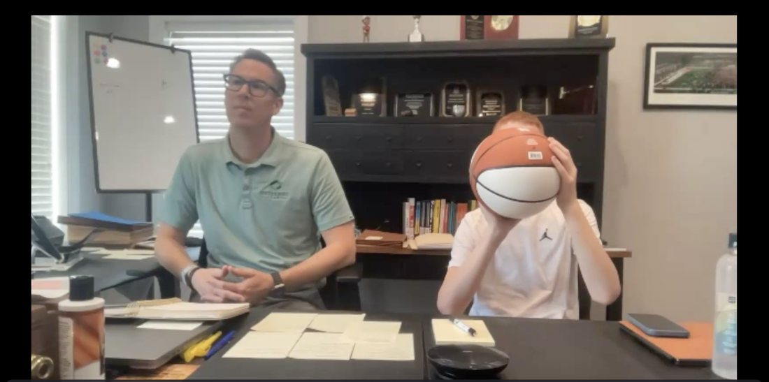 Live call with a player holding the ball up to show his hand placement while a parent sits in on the call